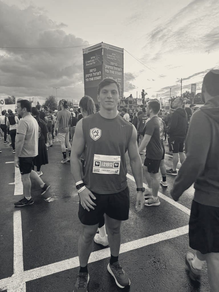 Ashtin Reich at the start line of a race, wearing an Israel-branded singlet.